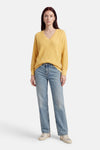 Pull jaune à col en V de FREEQUENT, porté avec un jean bleu et des baskets.