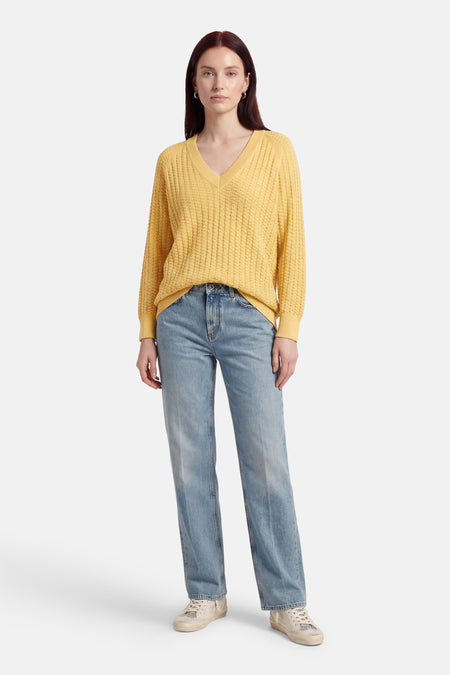 Pull jaune à col en V de FREEQUENT, porté avec un jean bleu et des baskets.