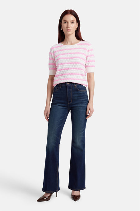 Pull multicolore de FREEQUENT à rayures roses et blanches, porté avec un jean évasé et des escarpins marron.