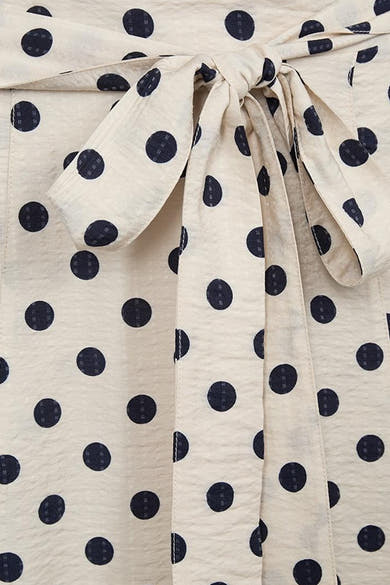Jupe mi-longue beige à pois noirs de FREEQUENT, avec un nœud décoratif à l'avant et un tissu légèrement froissé.