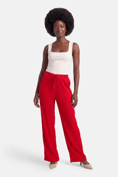 Pantalon plissé rouge de FREEQUENT, ample avec cordon de serrage, porté avec un débardeur blanc et des talons nude.