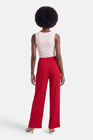 Pantalon rouge de FREEQUENT plissé, porté avec un débardeur rose clair et des escarpins beiges, vue de dos.