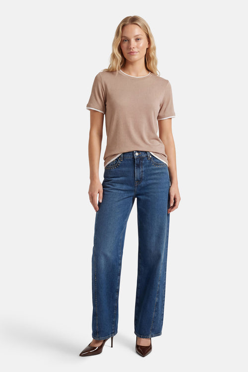 T-shirt beige à manches courtes de FREEQUENT, avec col et bordures de manches blancs, porté avec un jean et des escarpins marron.
