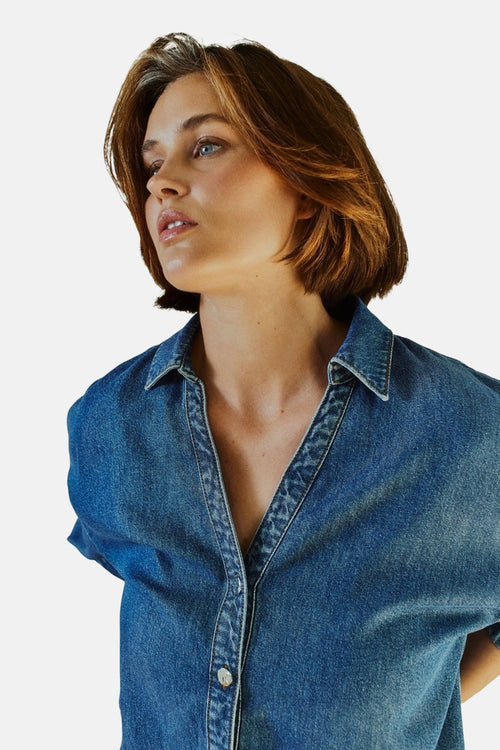 Chemise en jean bleu moyen de FREEQUENT avec col pointu, boutonnage blanc et décolleté en V, portée par une femme.