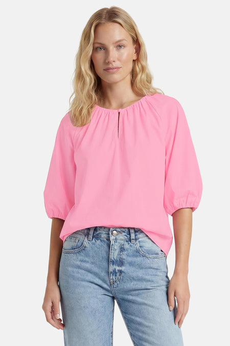 Blouse rose de FREEQUENT avec encolure froncée à fente, manches bouffantes 3/4, portée avec un jean bleu.