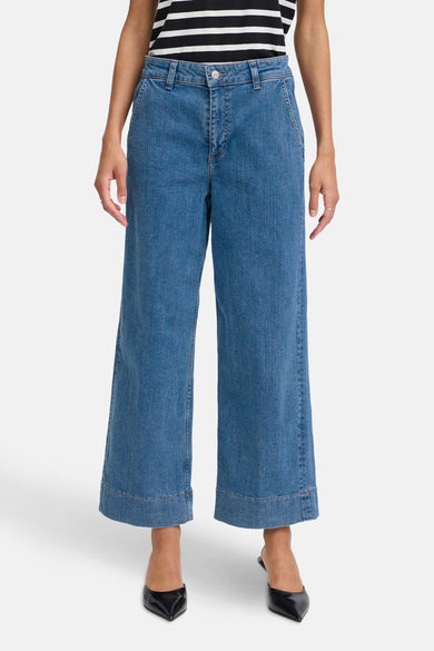 Jean large en denim bleu clair de B.YOUNG, porté avec un haut rayé noir et blanc et des chaussures noires pointues.
