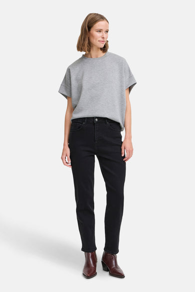 Jean mom en denim noir de B.YOUNG, porté avec un T-shirt gris et des bottines en cuir bordeaux.