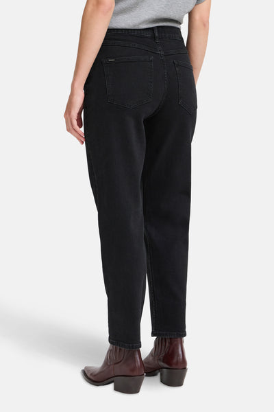 Jean Mom en denim noir de B.YOUNG, avec des poches arrière et porté avec des bottines marron.
