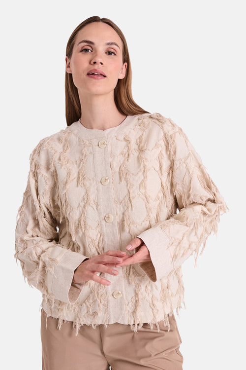 Chemise à manches longues beige de FREEQUENT, texturée avec motifs décoratifs, portée avec un pantalon beige.

