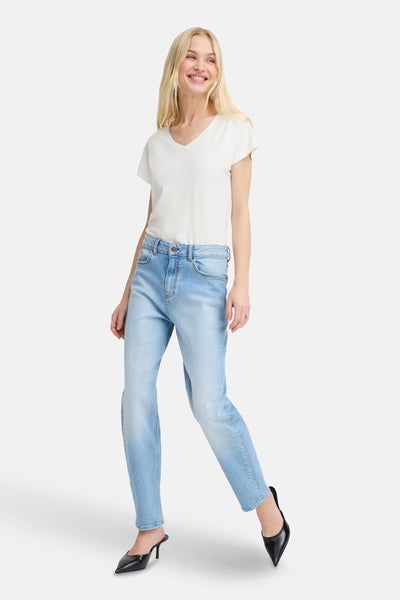 Top uni manches courtes blanc par B.YOUNG, porté avec un jean bleu et des escarpins noirs.
