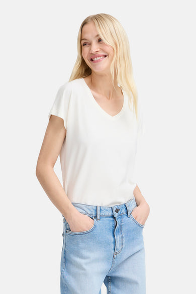 Top uni manches courtes blanc de B.YOUNG, porté avec un jean décontracté, mains dans les poches, et un sourire.