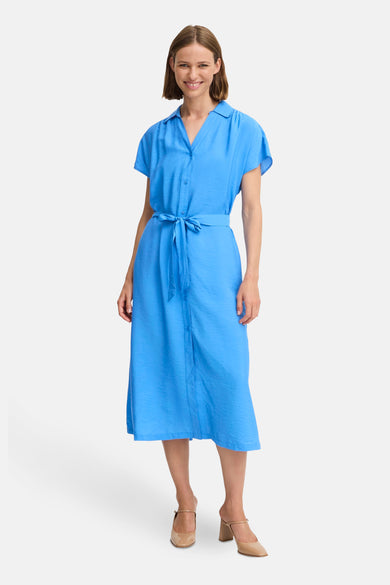 Robe bleu de B.YOUNG, mi-longue avec une ceinture assortie, portée avec des chaussures à talons beiges.
