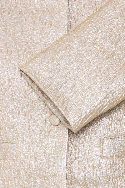 Korte beige jas van B.YOUNG, getextureerd met een zichtbare knoop en de mouwboord in close-up.