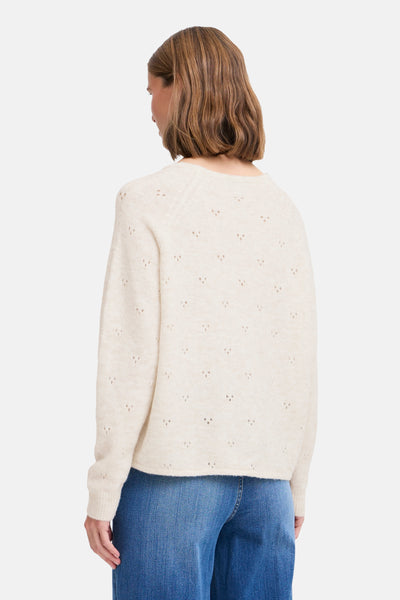 Pull à col rond écru par B.YOUNG, avec motifs ajourés triangulaires, porté avec un jean bleu.