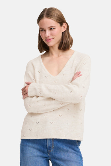 Pull écru à col rond de B.YOUNG, orné de motifs ajourés, porté avec un jean bleu.
