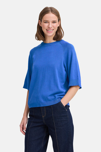 Pull à col rond bleu de B.YOUNG, porté avec un pantalon foncé, sur fond clair.
