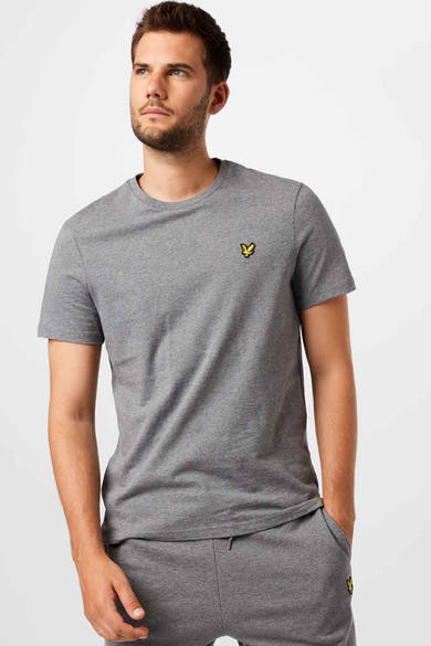 T-shirt gris de LYLE & SCOTT, avec un logo jaune brodé sur la poitrine, porté avec un pantalon de survêtement assorti.