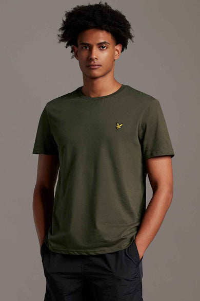 Olive green short-sleeve t-shirt with small yellow bird logo on chest, worn by model in front view, paired with dark pants
