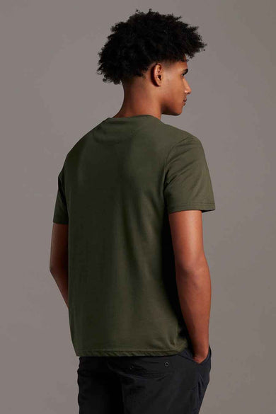 Olive green short-sleeve t-shirt from back view, plain cotton fabric, worn with dark pants