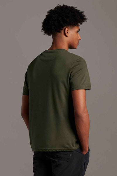 Olive green short-sleeve t-shirt from back view, plain cotton fabric, worn with dark pants