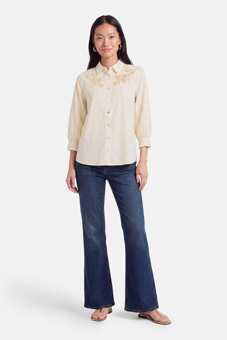 Chemise à manches courtes multicolore par FREEQUENT, rayures fines crème et jaune, broderie florale dorée, vue frontale sur modèle en jeans bleus et sandales dorées
