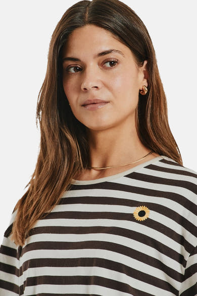 Multicolored short-sleeve striped T-shirt with sunflower patch, round neckline, and relaxed fit, shown on model in lifestyle crop.