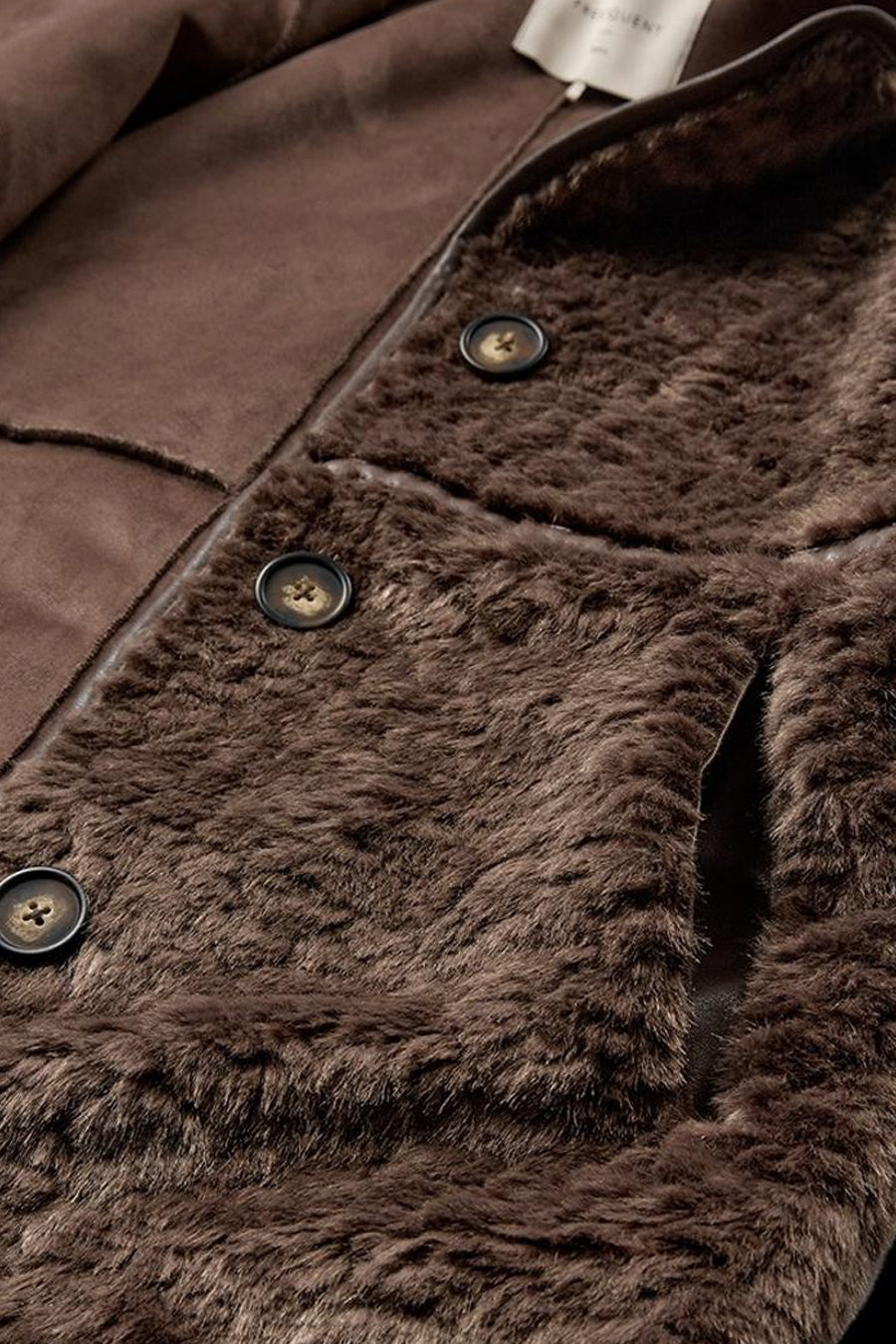 Détail de la veste longue taupe FREEQUENT avec doublure imitation fourrure et boutons.