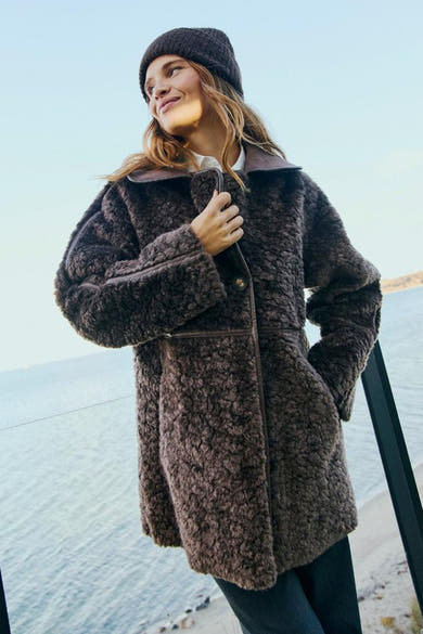 Veste longue taupe FREEQUENT portée par une femme, avec col et fermeture boutonnée.