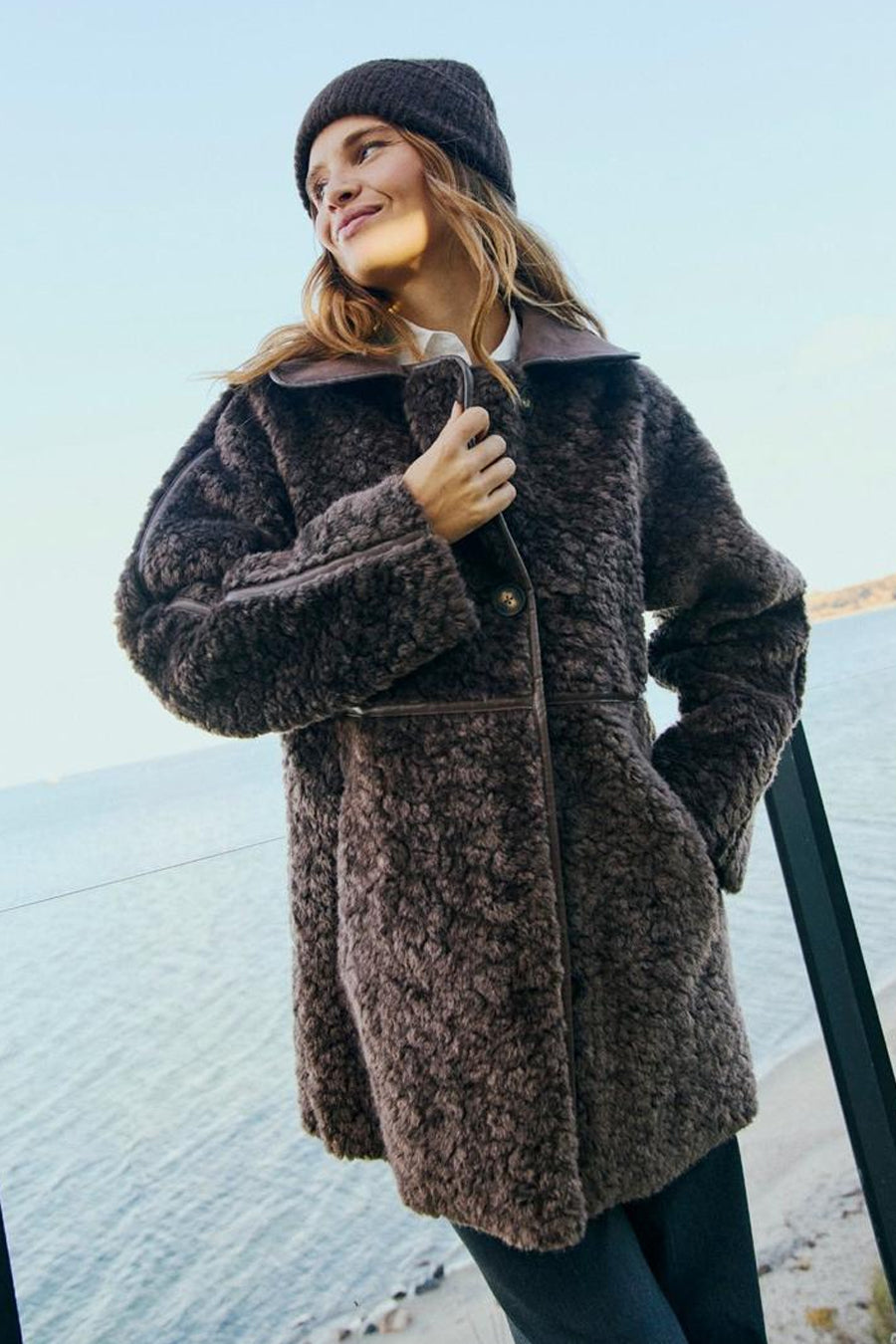 Veste longue taupe FREEQUENT portée par une femme, avec col et fermeture boutonnée.