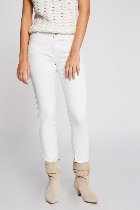 Pantalon blanc de Morgan de Toi, coupe skinny, porté avec des bottines beiges en daim.
