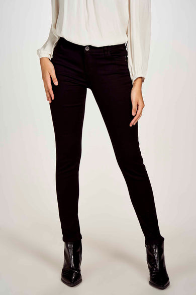 Pantalon noir moulant de Morgan de Toi, porté avec un chemisier blanc à manches longues et des bottines noires vernies.