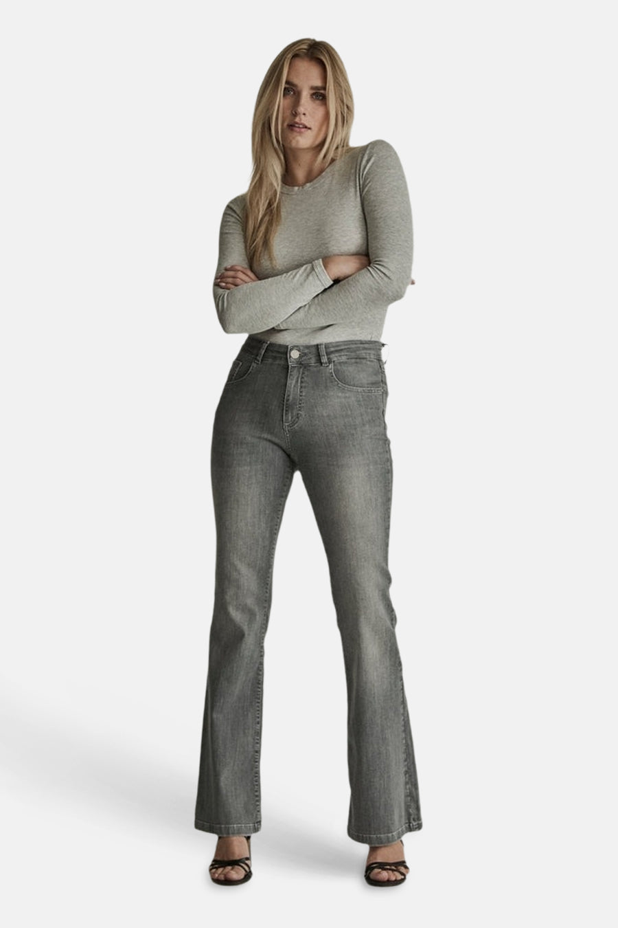 Light grey flared jeans by JADE, featuring a high waist, classic five-pocket design, and subtle fade, worn with a long-sleeve top and strappy sandals in a full front view.