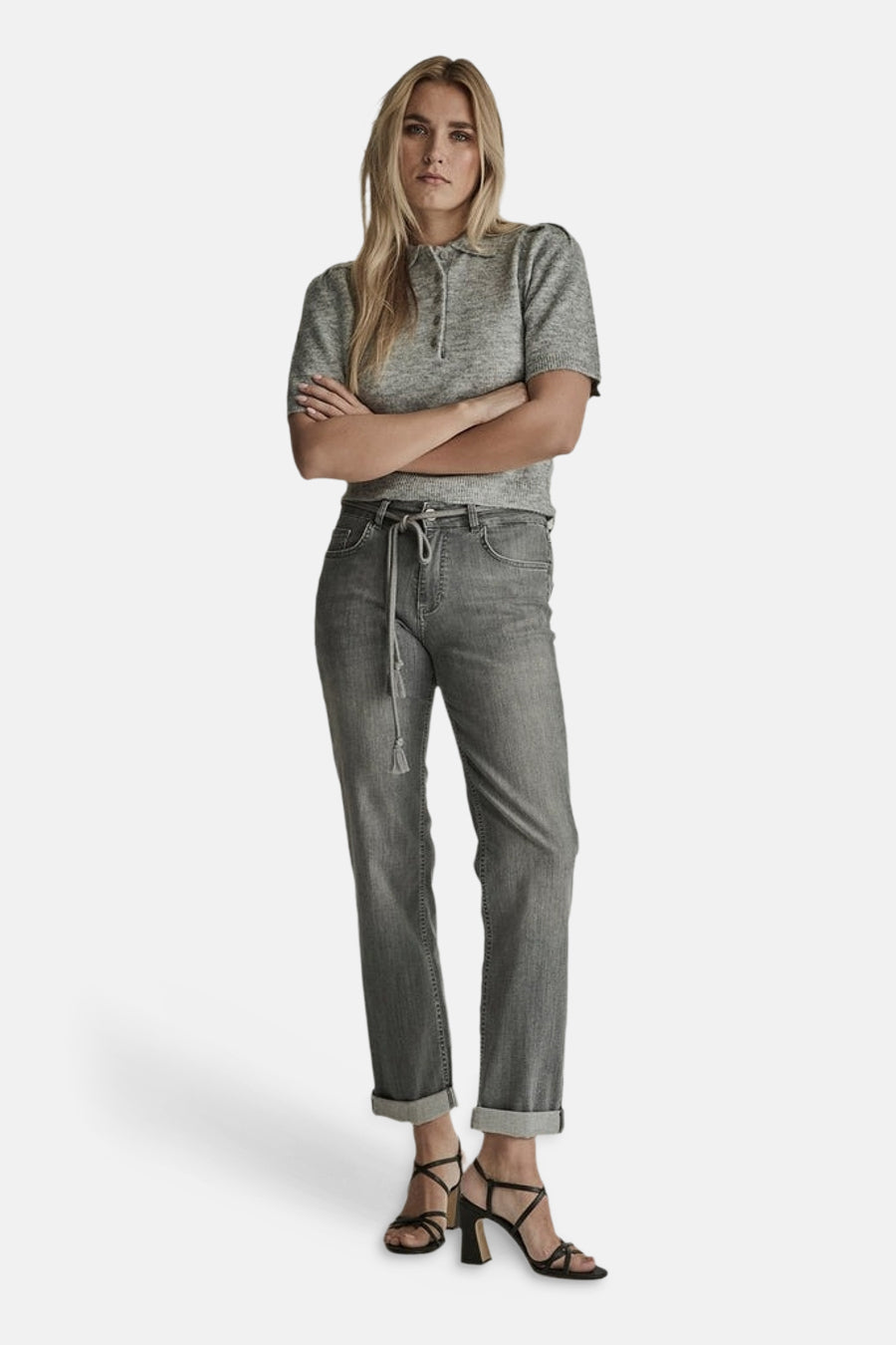 Light grey straight-leg denim jeans with drawstring waist and cuffed hems, worn with a grey short-sleeve top and black strappy heels, full-length front view.