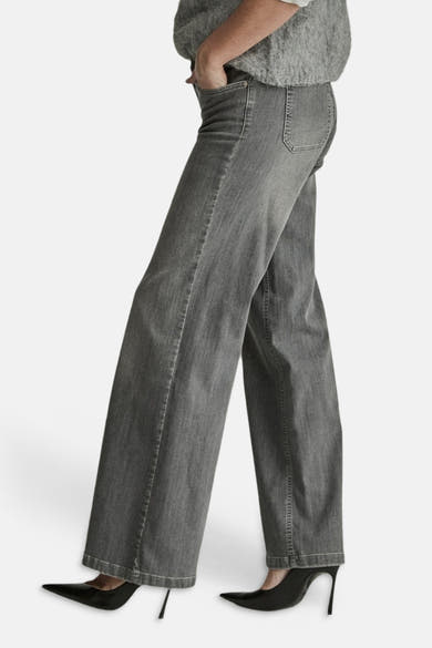 Light grey wide-leg denim jeans by MIRA, side view, featuring classic stitching and relaxed fit, worn with black heels.