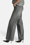 Light grey wide-leg denim jeans by MIRA, side view, featuring classic stitching and relaxed fit, worn with black heels.