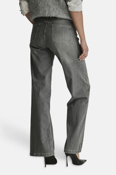 Light grey wide-leg denim jeans by MIRA, back view with faded wash and classic stitching, worn with black heels
