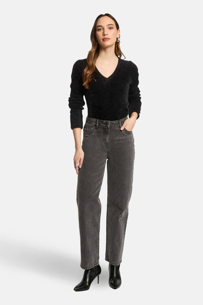 Zwarte V-hals trui van Morgan de Toi, in pluizige brei, gedragen met een grijze jeans en zwarte enkellaarsjes.