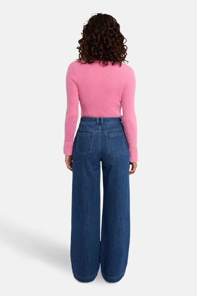 Roze V-hals trui van Morgan de Toi, met lange mouwen, gedragen met een wijde blauwe jeans.
