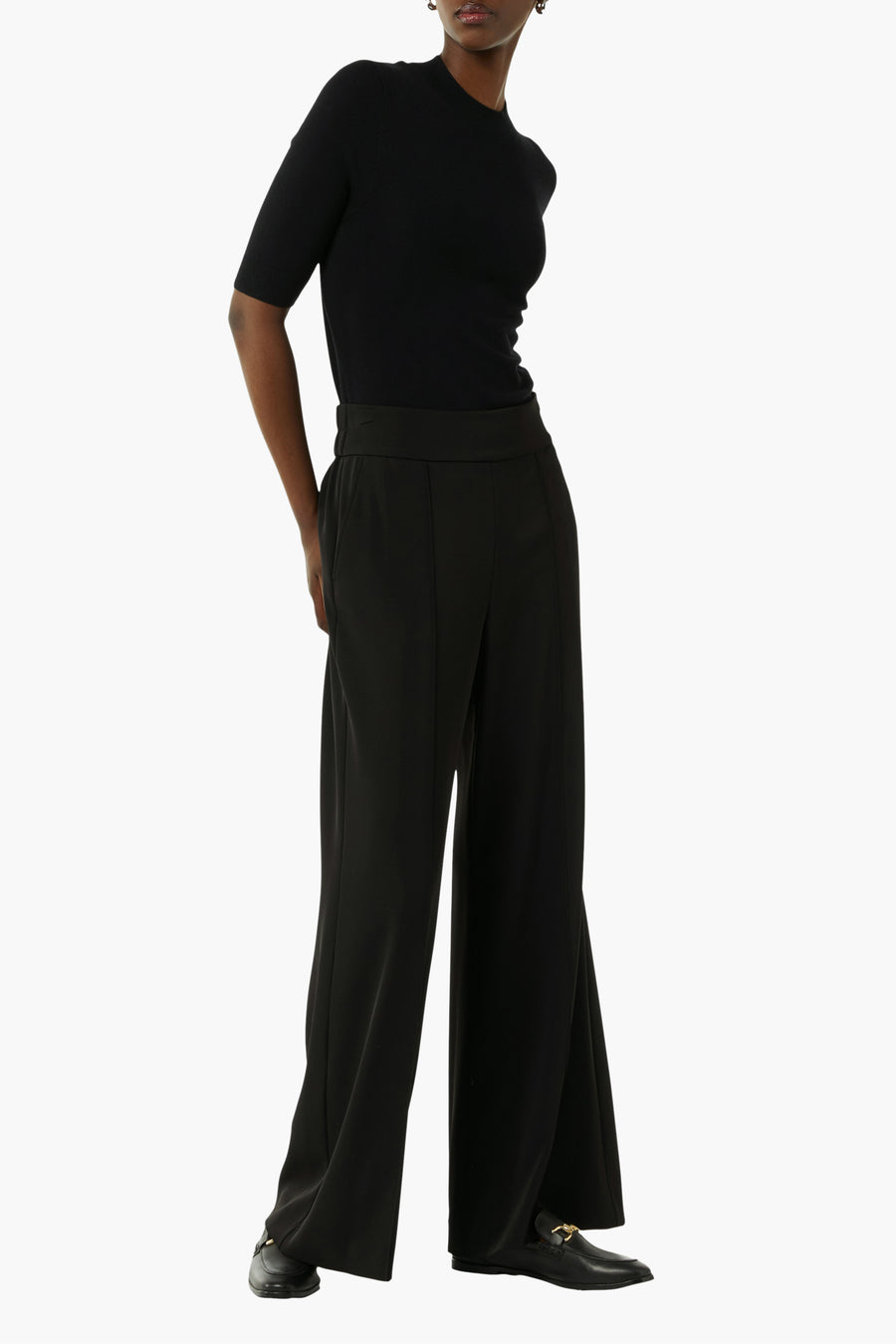Pantalon de costume noir de COMMA, jambes larges, avec poches et porté avec un top noir à manches courtes.