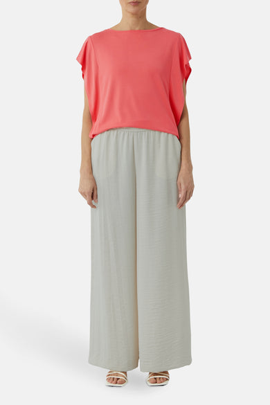 Koraalkleurig blouse met korte mouwen van COMMA, gedragen met een lichtgrijze wijde broek.