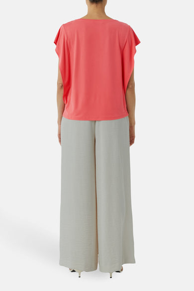 Blouse corail à manches courtes de COMMA, portée avec un pantalon large gris clair.