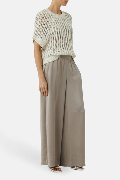 Beige ronde hals trui van COMMA met een opengebreid patroon, gedragen met een wijde, vloeiende broek.