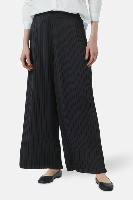 Blauwe broek van COMMA met plooien, wijd en lang, gedragen met een wit overhemd.