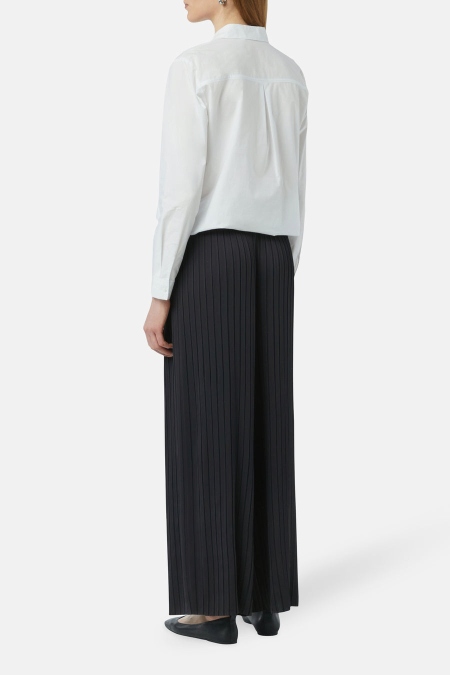 Pantalon bleu de COMMA à plis, ample et long, porté avec une chemise blanche.