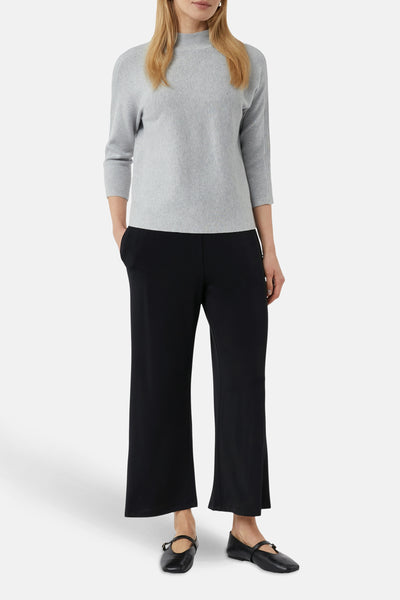 Pull gris de COMMA, à manches trois-quarts, porté avec un pantalon noir et des chaussures plates.
