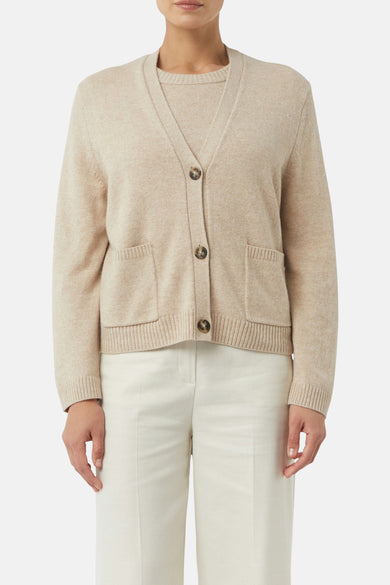 Beige cardigan van COMMA, gedragen met een crèmekleurige pantalon met rechte pijpen en sandalen.