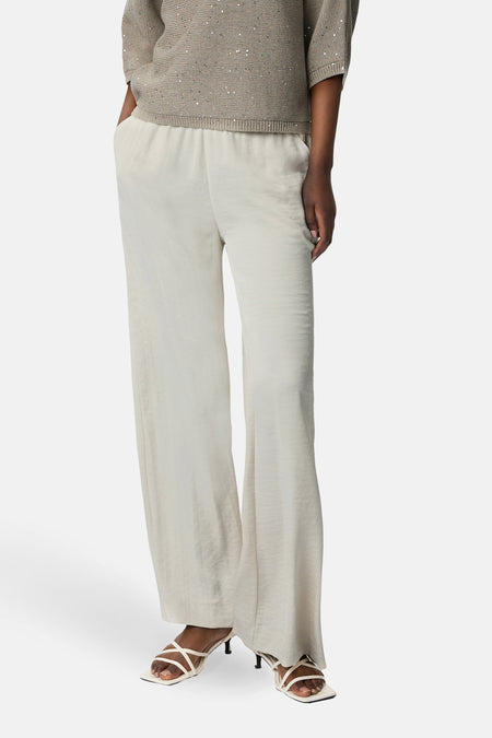 Ecru broek van COMMA, wijd en vloeiend, gedragen met een beige trui met pailletten.