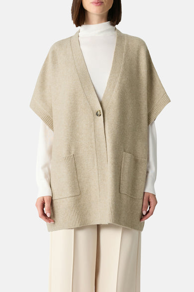 Beige gilet van COMMA, met korte mouwen, enkele knoop en opgestikte zakken, gedragen over een witte trui en een crèmekleurige broek.