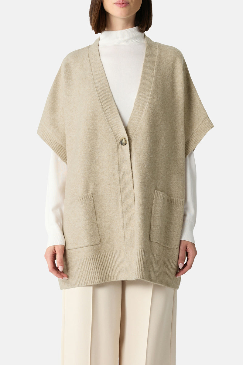 Beige gilet van COMMA, met korte mouwen, enkele knoop en opgestikte zakken, gedragen over een witte trui en een crèmekleurige broek.