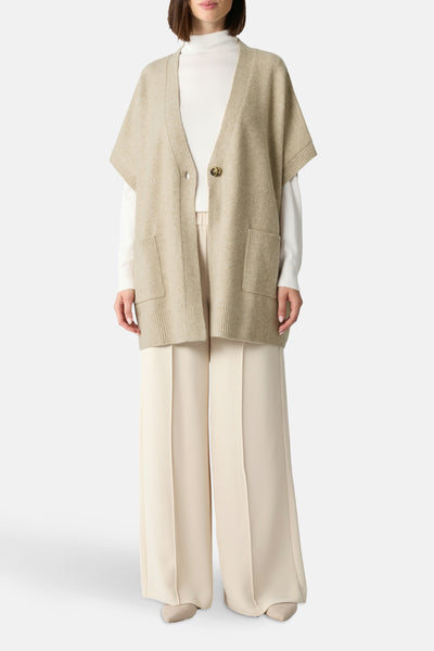 Beige gilet van COMMA met opgestikte zakken, gedragen over een coltrui en een wijde witte broek.